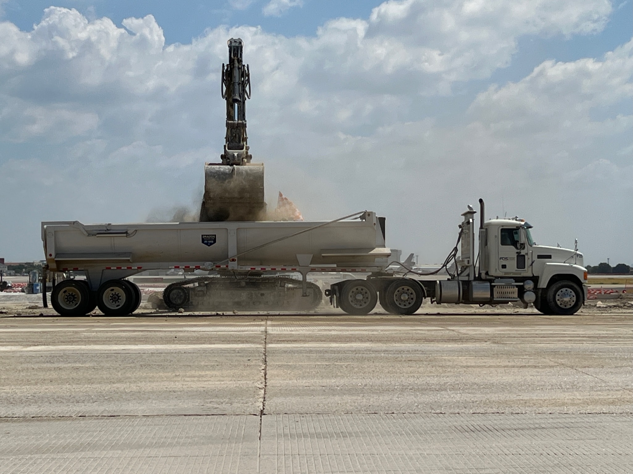 FOS Logistics truck being loaded by excavator at a construction project